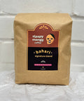 Kraft paper coffee bag with 'sleepy mango coffee' branding on a white textured background