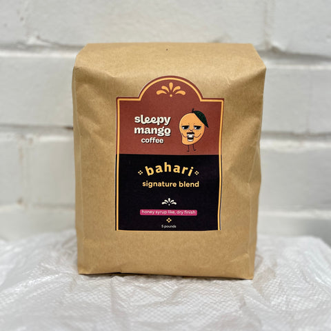 Kraft paper coffee bag with 'sleepy mango coffee' branding on a white textured background